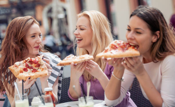 istock Female friends eating pizza in cafe 990086666