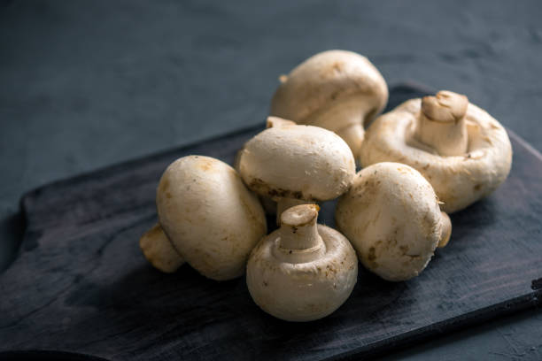 istock White champignons on the dark kitchen table. Cooking delicious dishes with mushrooms 990104612