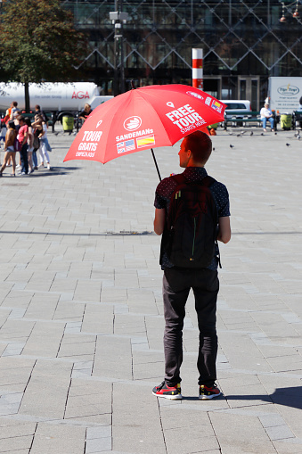 Copenhagen, Denmark - June 27, 2018: One of Sandemans free tour guides under his red umbrella at the Town hall square in downtown Copenhagen.