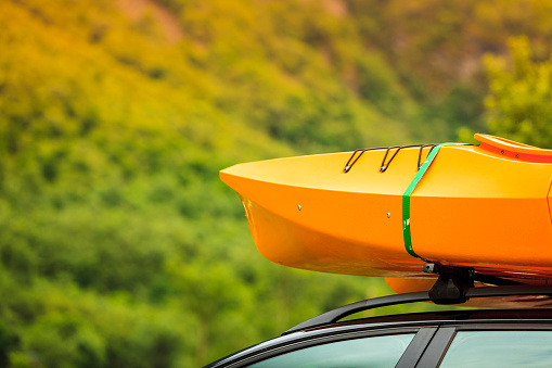 Active lifestyle sport concept. Car with kayak yellow canoe on top roof ready to transportation