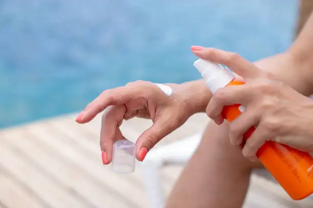 The girl applies sunscreen on her hand to protect the skin from sunburn. The concept of the season of holidays.