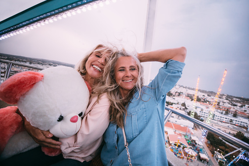 Happy senior women enjoying the view and having fun on funfair ferris wheel ride