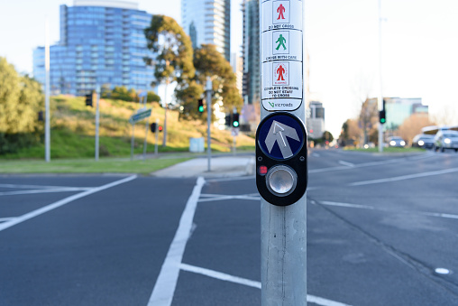 City traffic concept: Pedestrian press to go button at intersection on blurred urban background.