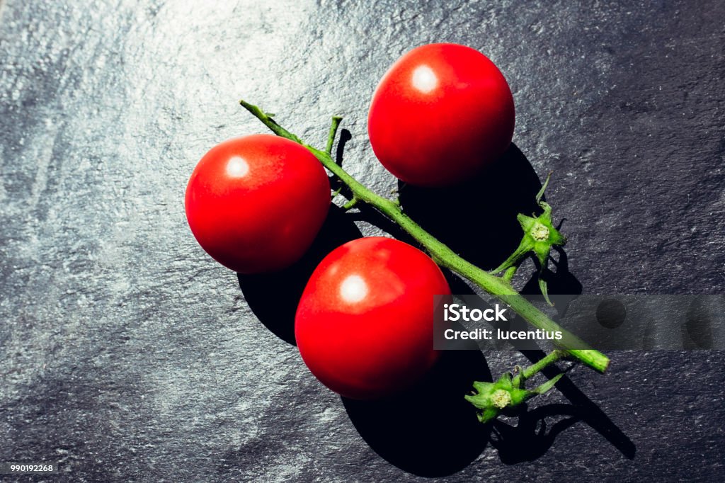 Three tomatoes on slate surface, Argb Three tomatoes on slate surface. Slate - Rock Stock Photo