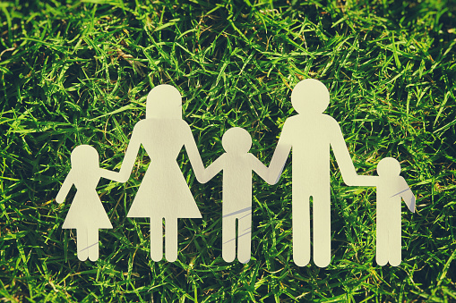 image of happy family concept. paper cut people holding hands together over green grass