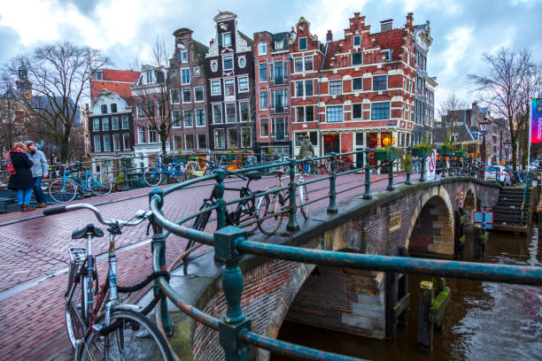 Amsterdam, Netherlands - December 14, 2017: Barges and houses along a canal in the centre of Amsterdam. Long exposure, Amsterdam Tranquil Canal Scene, Netherlands