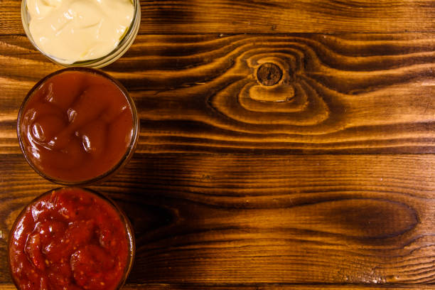 istock Different sauces in glass bowls on wooden table. Top view 990262972