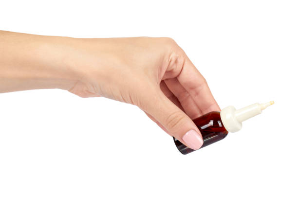 istock eye or ear drops glass bottle with hand isolated on white background. 990263498