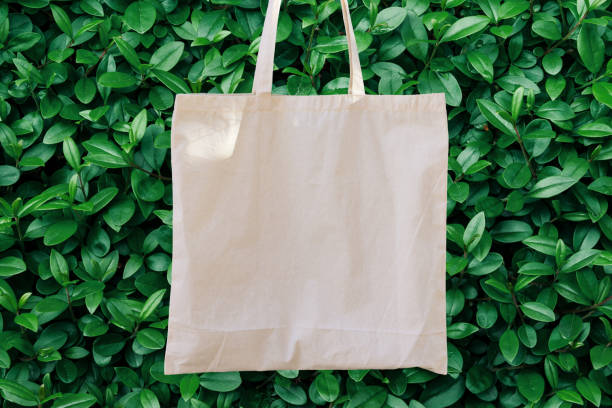 Blank White Mockup Linen Cotton Tote Bag on Green Bush Trees Foliage Background. Eco Nature Friendly Style. Environmental Conservation Recycling. Template for Artwork Text. Japanese maqueta en blanco de blanco lino de algodón bolso de mano sobre fondo de follaje de árboles de bush verde. estilo agradable de la naturaleza de eco. conservación del medio ambiente concepto de reciclaje. plantilla para el texto de la obra de arte. japon