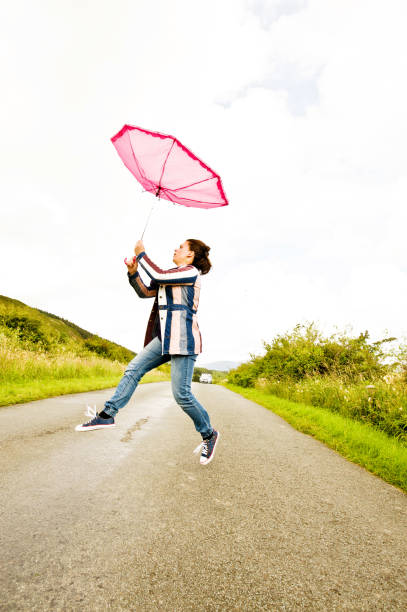 istock Stormy Weather: Woman Struggles With Pink Umbrella 990285678