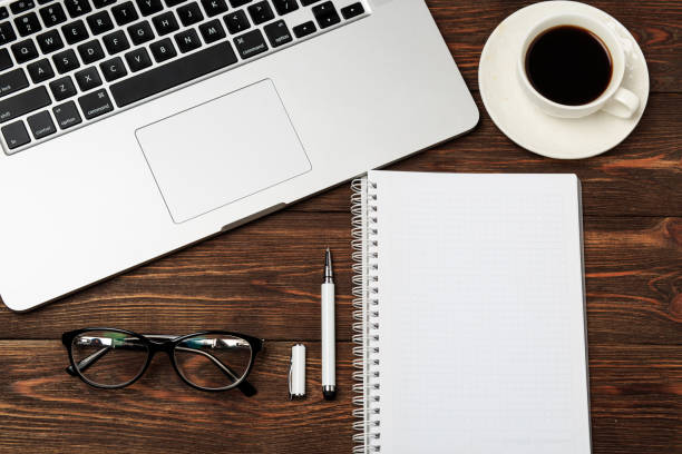 istock Office workplace with text space. Wooden table with office supplies tablet, coffee, keyboard and book, top view. Modern office workplace. Space for text. Office stuff. 990295318