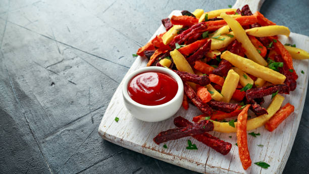 Homemade Baked Mixed Vegetable Fries beetroot, carrot and parsnip with ketchup. on white wooden board