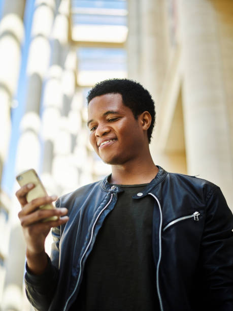 istock Low angle portrait of cheerful African American man using his cell phone while walking in the city 990304178
