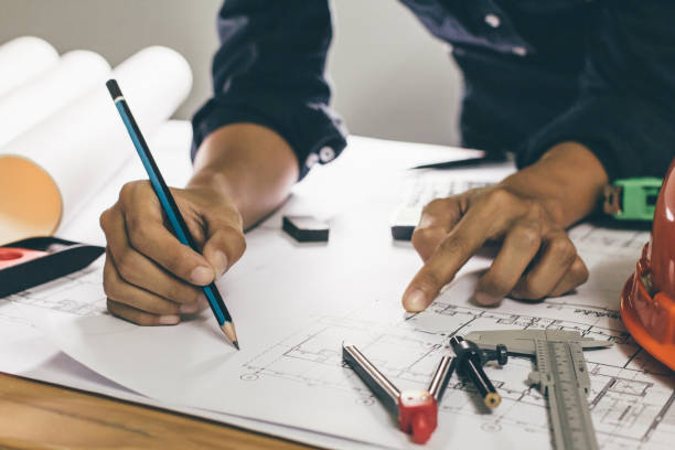 istock Concept architects,engineer holding pen pointing equipment architects On the desk with a blueprint in the office, Vintage, Sunset light.Selective Focus 990319738