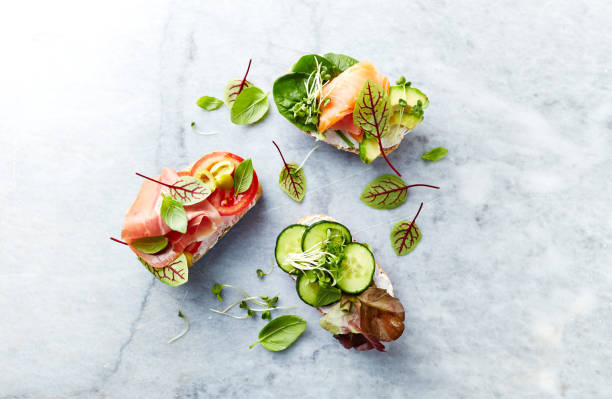 istock Healthy open sandwiches with vegetables, herbs, salmon, ham, herbs and soft cheese. Flat lay. Healthy diet concept. 990328452