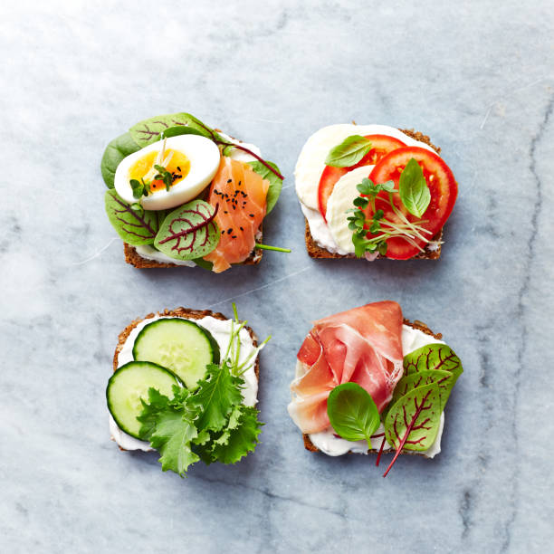 istock Healthy open sandwiches with vegetables, egg, herbs, salmon, ham,  mozzarella and soft cheese. Flat lay. Healthy diet concept. 990328458