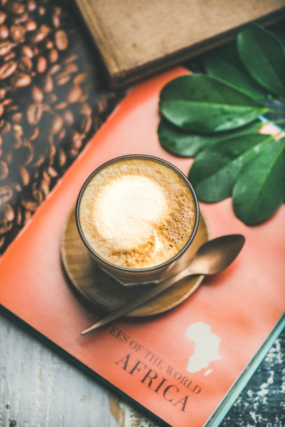 istock Cappuccino coffee in glass over table with bright magazine background 990336114