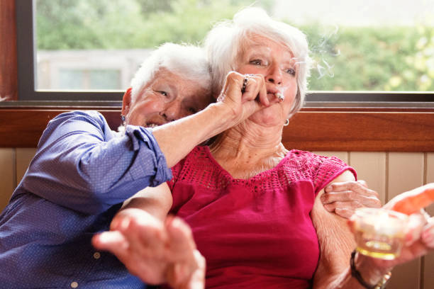 Two senior girlfriends 83 years old smoke marijuana together Two senior girlfriends 83 years old smoke medicinal marijuana together. One of them shows the other how to do. The old lady is surprise and making a face.. They have hair and wear casual clothes. The recreational marijuana become legal in Canada next autumn. Photo was taken in Quebec Canada. smokers wrinkles stock pictures, royalty-free photos & images