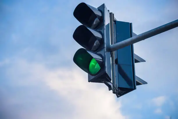 The green streetlight signal with cloudy blue skies in the background.