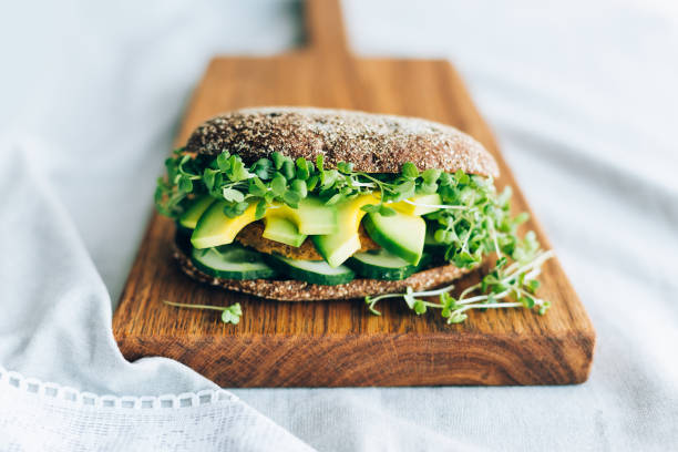 Vegetarian burger with cucumber, avocado, microgreen mustard on a wooden board
