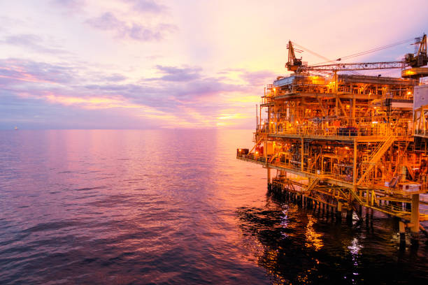 plataforma de construção offshore para exororation e produção de petróleo e gás com ponte no tempo para poder energia do wolrd conceito da noite. - oil pumping unit at sunset time - fotografias e filmes do acervo