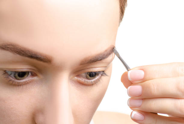 istock Female eyebrow shape brown eye eyebrow tweezers 990375350