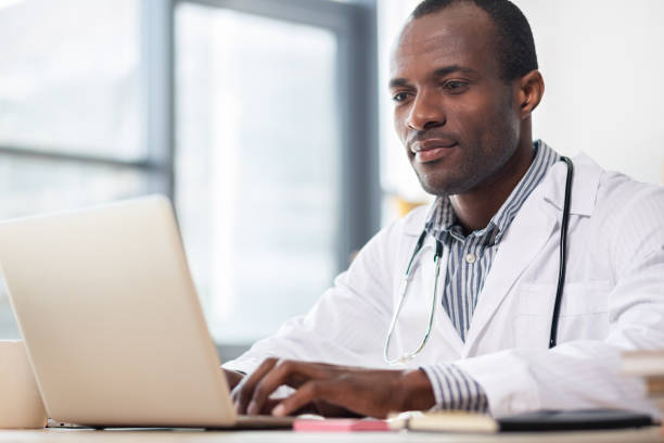 istock Pleased dark-skinned practitioner reading news 990398726
