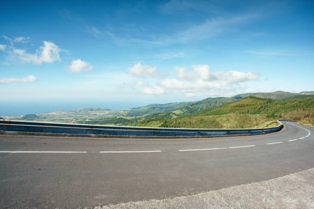 青い空と海を背景に山の道路を回します。海の眺めと草が茂った丘によってカーブの多い道路。サンミゲル島、アゾレス諸島。ポルトガル。 - road beach sky cloud ストックフォトと画像