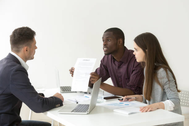 istock African American worker blaming Caucasian partner for document mistake 990458696