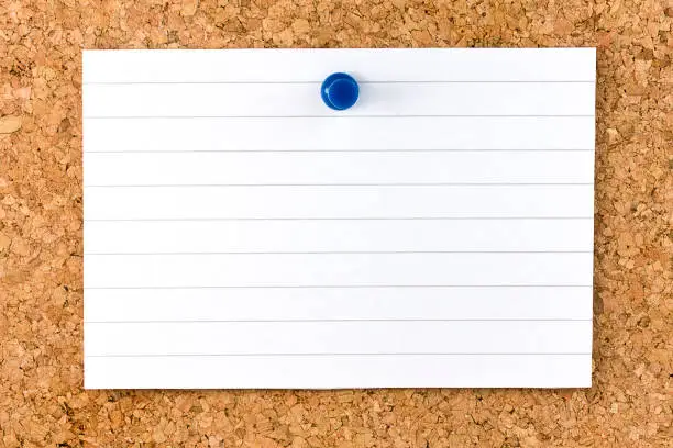 Horizontal Blank white striped sheet fixed on cork board with a blue small thumb tack