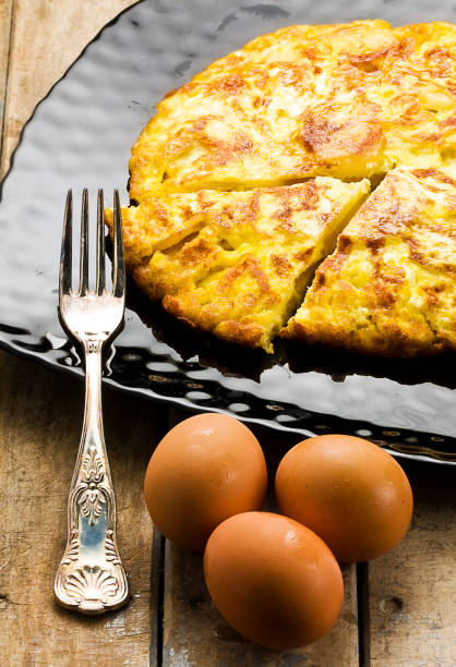 istock Sliced omelet on black plate and whole brown eggs on rustic wooden table 990463072
