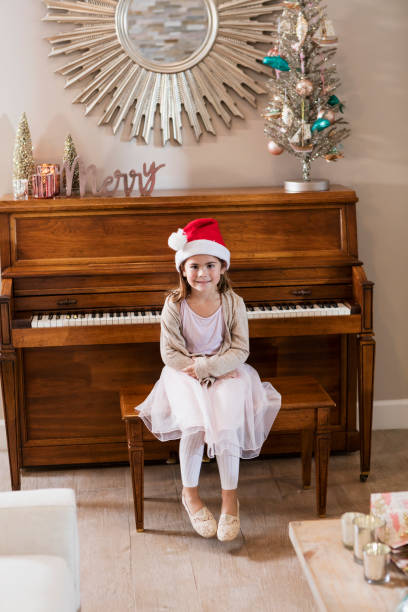 istock Mixed race girl sitting on piano bench with Santa hat 990465488