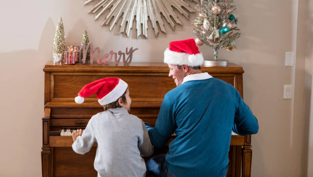 istock Father and son sitting at piano, Santa hats 990465532