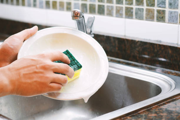 istock Hands in rubber gloves washing dishes with spon 990481076