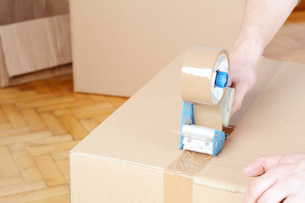 istock Man sealing a shipping cardboard box 990481110