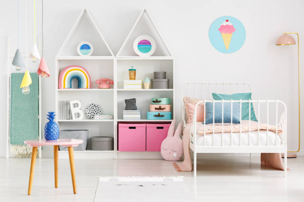 vista frontal de la habitación de un niño con una tabla, estantes con cajas y arco iris, cama individual y helado de póster en la pared - colores fotos fotografías e imágenes de stock