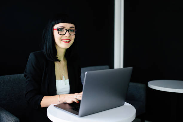 istock Beautiful brunette sitting at the table and using laptop in cafe 990530600