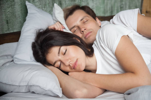 coppia millenaria che dorme tranquillamente in un letto accogliente - spooning love embracing men foto e immagini stock