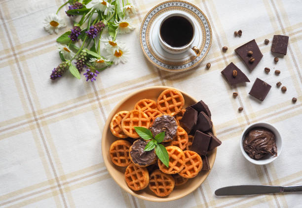 Round Belgian waffles with chocolate cream on a textile napkin.