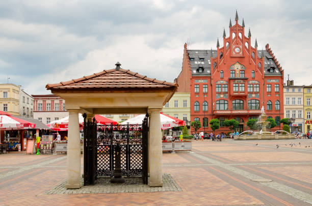 artesian well, town hall in the background, old market square in chojnice, poland. - pomorskie province imagens e fotografias de stock