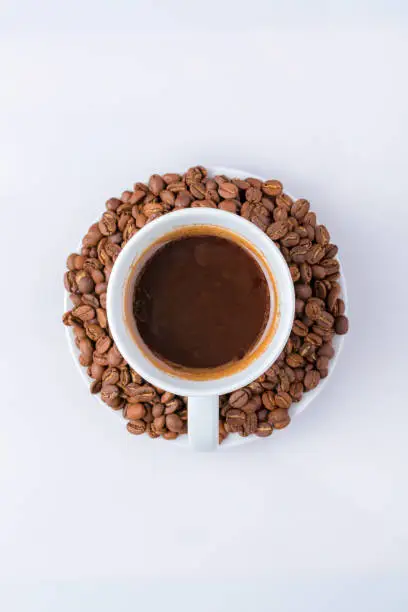 A cup of coffee and roasted coffee beans on a white background