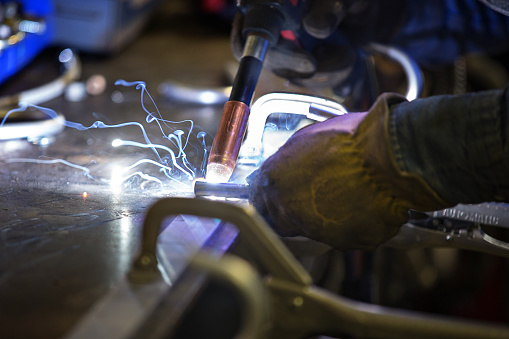 The workshop scene capturing the artistry of a welder using a torch.