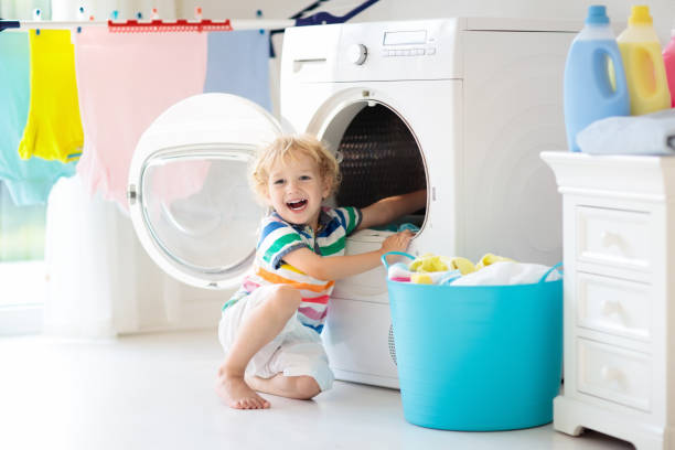 Child in laundry room with washing machine Child in laundry room with washing machine or tumble dryer. Kid helping with family chores. Modern household devices and washing detergent in white sunny home. Clean washed clothes on drying rack. fabric softener photos stock pictures, royalty-free photos & images