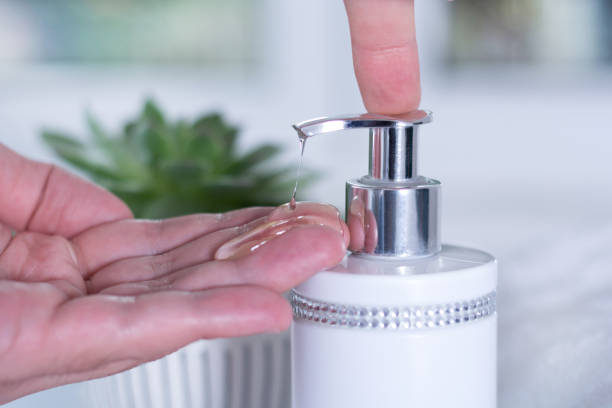 Finger push button on liquid soap bottle in clean gently hand in bathroom
