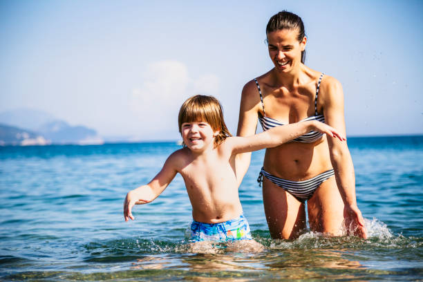 istock Mother and son having fun in sea 990598686