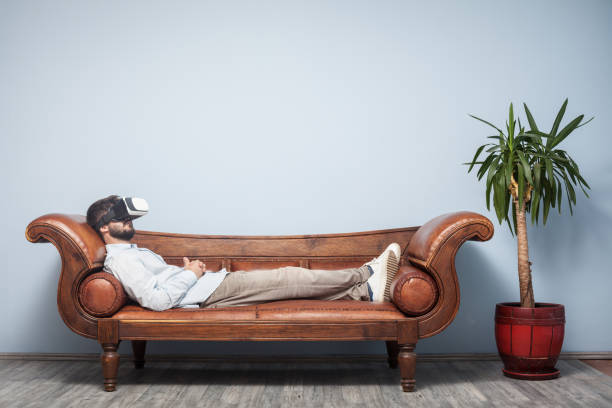 adult man with vr headset lying down on psychiatrist couch - psychiatrists couch imagens e fotografias de stock