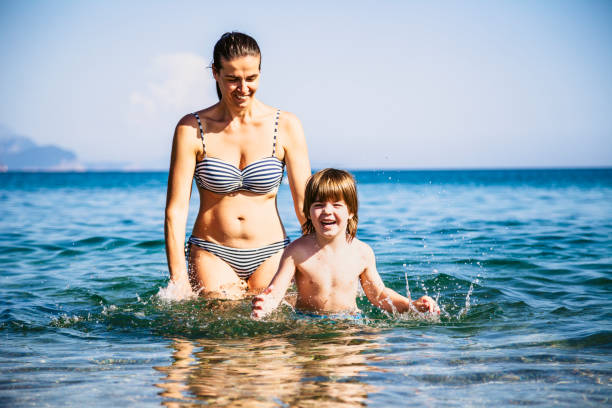 istock Mother and son having fun in sea 990599604