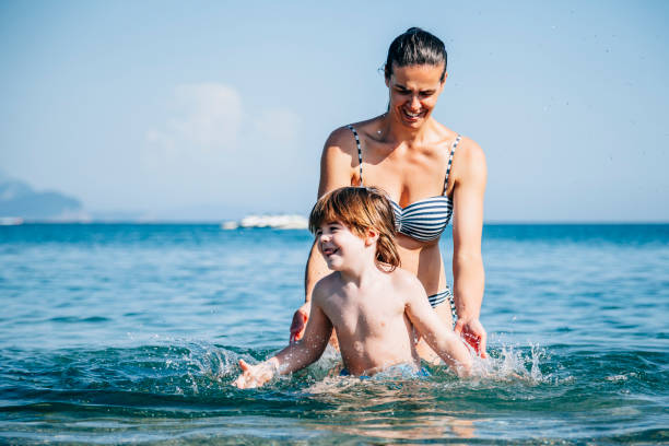 istock Mother and son having fun in sea 990611826