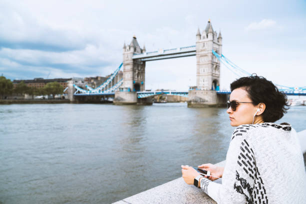 istock Young woman using mobile phone, Tower Bridge at the background 990612442