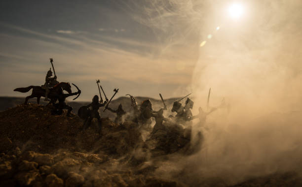 istock Medieval battle scene with cavalry and infantry. Silhouettes of figures as separate objects, fight between warriors on sunset foggy background. 990635740